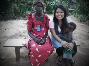 Towson alumna Angie Hong with a Ugandan mother and child during her recent volunteer trip.