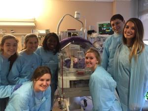 The Towson University Holliday Committee visit with a new friend after delivering blankets to the Neonatal Intensive Care Unit at GBMC Hospital.
