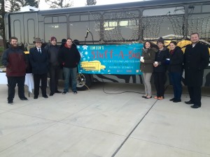 Members of the Veterans Center staff and numerous volunteers stand in front of the "Stuff-a-Bus" bus on Monday evening. The lighting of the bus signifies the beginning of the "Stuff-a-Bus" event. 